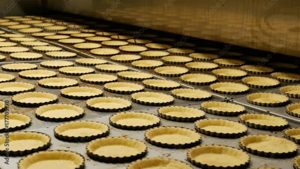 Industrial process of Empty Pies base pastries made from biscuits and butter on a conveyor belt in a bakery factory