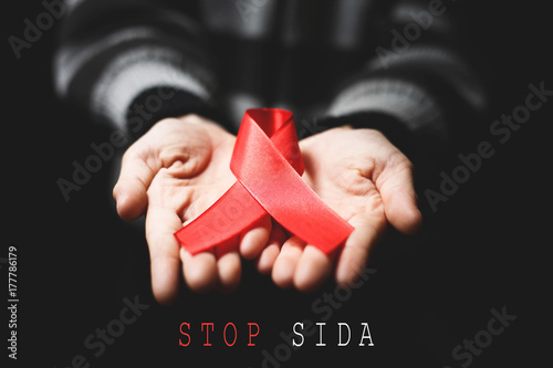Red ribbon on palms and text STOP SIDA