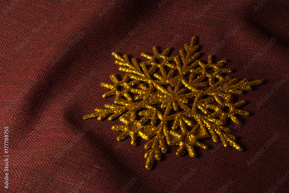 One big golden snowflake on the dark cloth background