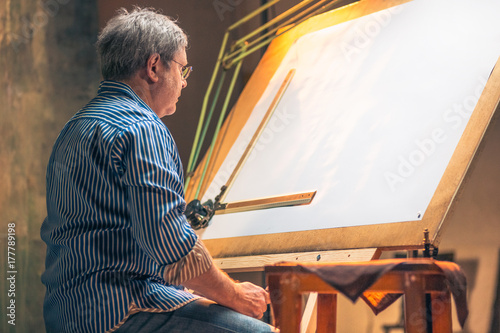 The mature creative engineer working with project on drawing board