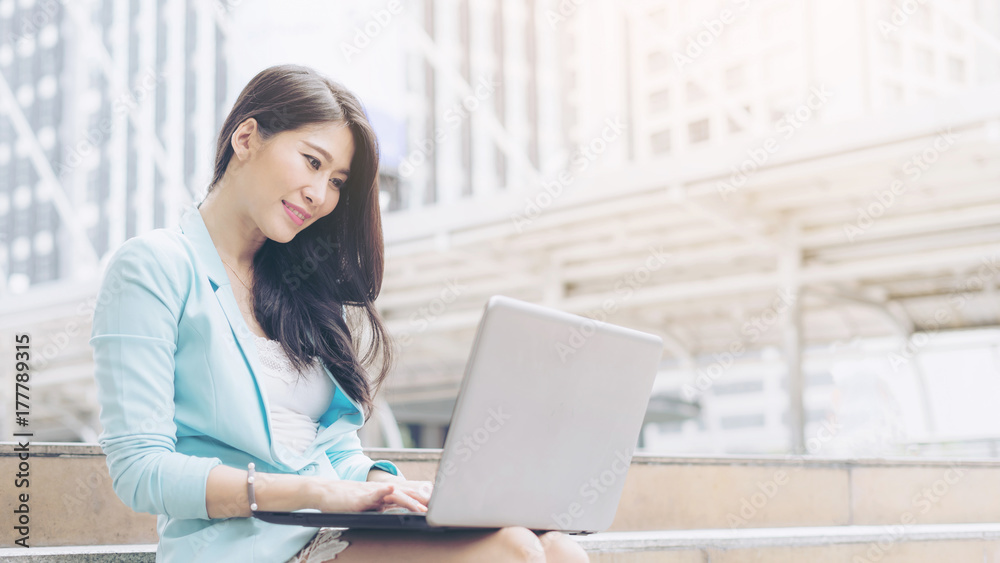 Beautiful cute girl smiling in business woman clothes using laptop computer , urban city background Beautiful cute girl smiling in business woman clothes using laptop computer , urban city background