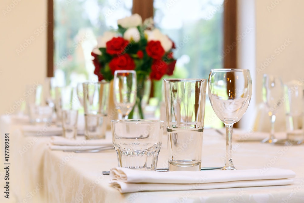 Beautifully set festive table, decorated with a bouquet of roses. The preparations for the party Beautifully set festive table, decorated with a bouquet of roses. The preparations for the party