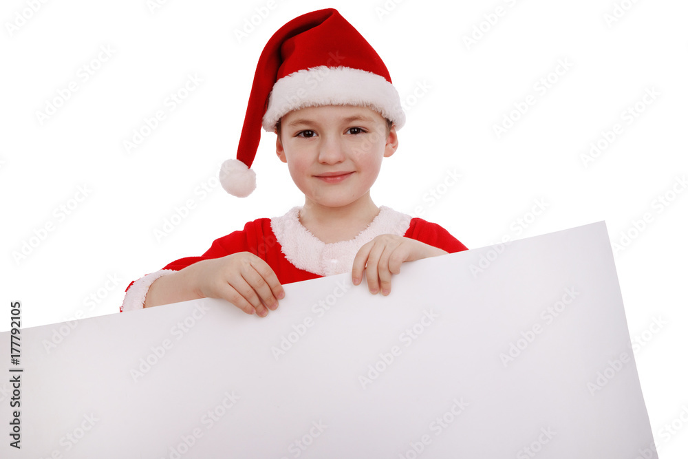 Boy in a suit of Santa Claus holds a white banner label isolated on white background Boy in a suit of Santa Claus holds a white banner label isolated on white background