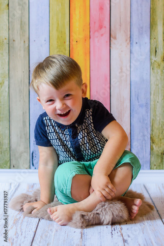 laughing kid play on wooden background on floor. Little caucasian child playing on colorful  wooden background indoor. happy Kid boy having fun at home