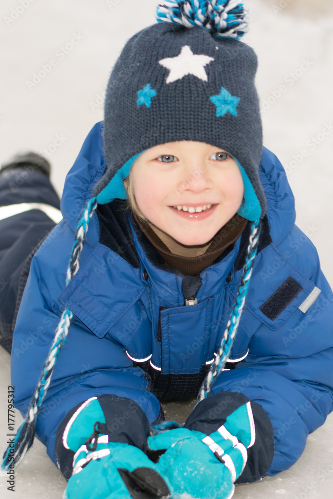 Happy boy lying in a snow - winter leisure for children