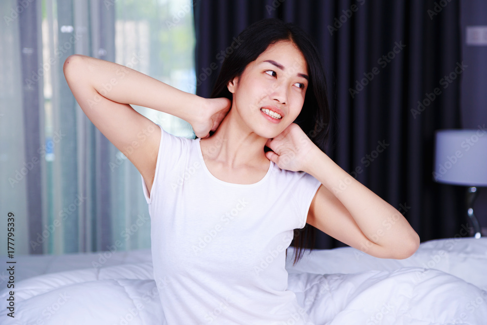 Woman waking up and hand raised on bed in bedroom Woman waking up and hand raised on bed in bedroom