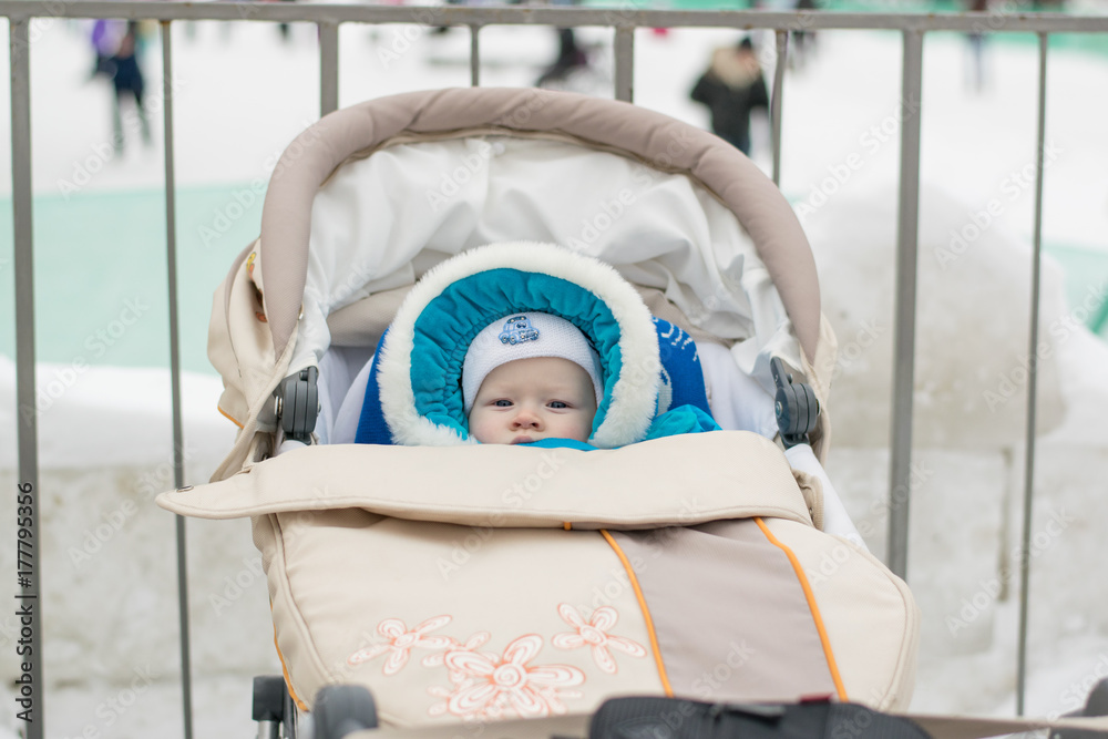 Baby in a perambulator (baby carriage) at a winter day