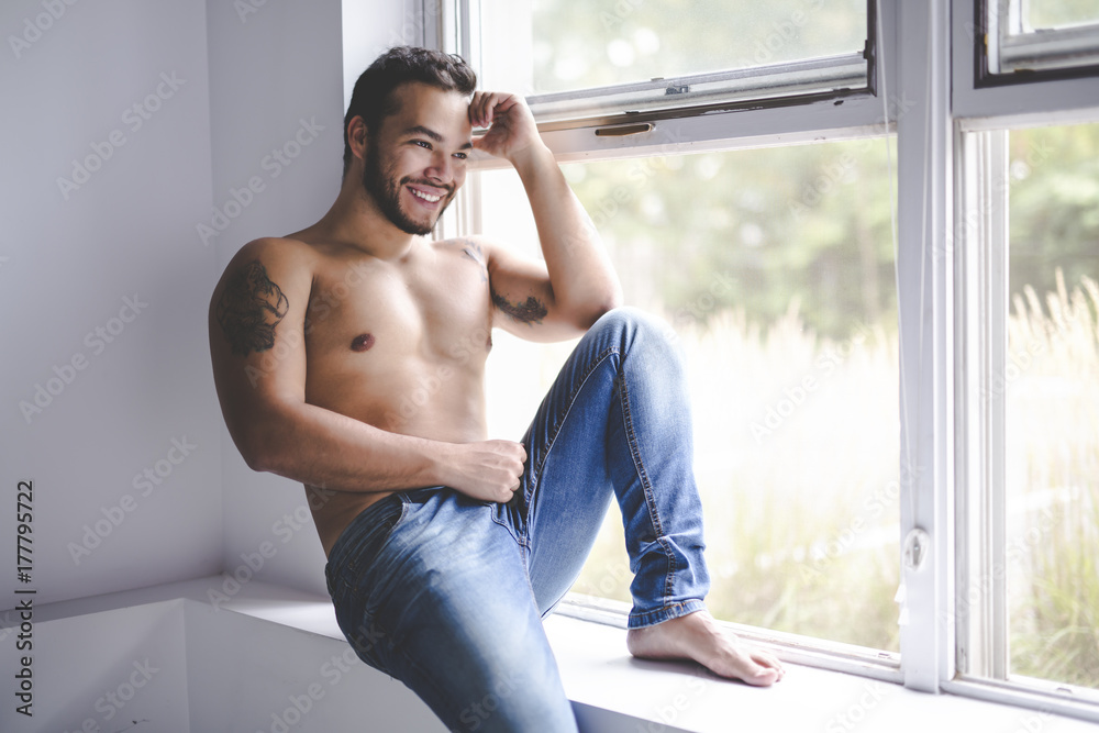 Sexy fashion portrait of a hot male model in stylish jeans with muscular body