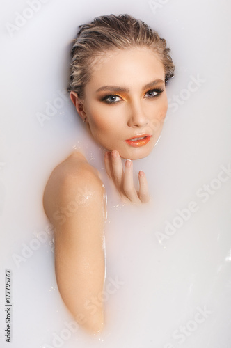 portrait of a blonde girl in milk, looking at the camera