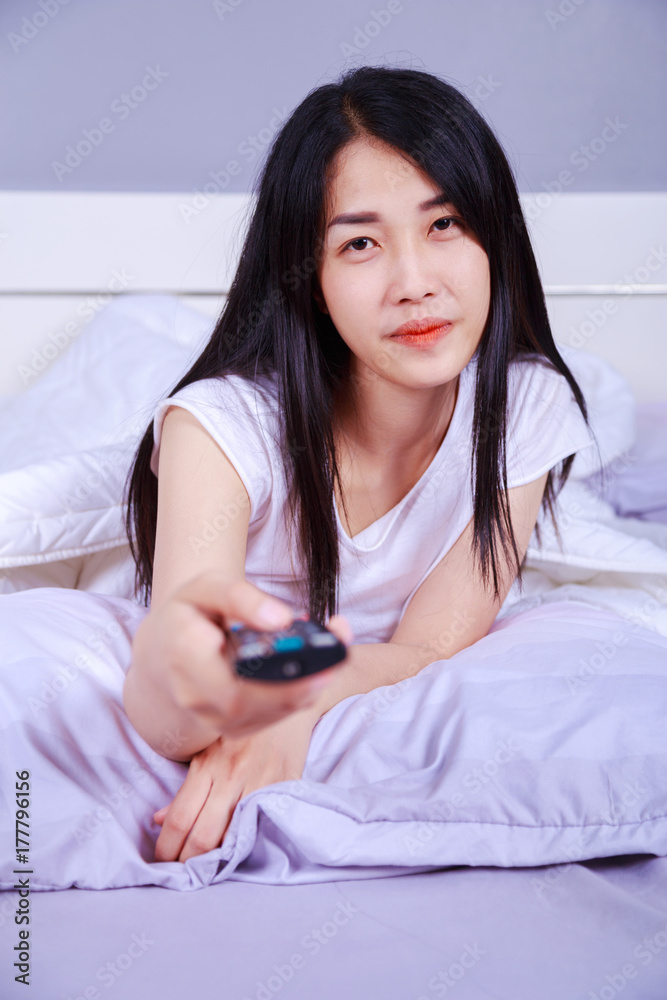 woman watching tv with remote on bed in bedroom woman watching tv with remote on bed in bedroom