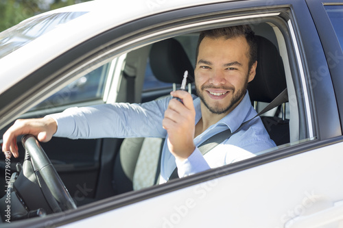 Closeup portrait, young cheerful, joyful, smiling, men holding up keys to her first new car