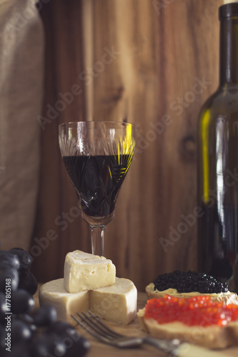 Fototapeta Naklejka Na Ścianę i Meble -  A glass of red wine, Brie cheese, grapes and caviar, shallow depth of field
