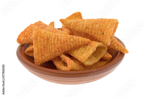 A small red clay bowl filled with cheese flavored cone shaped corn chips isolated on a white background.