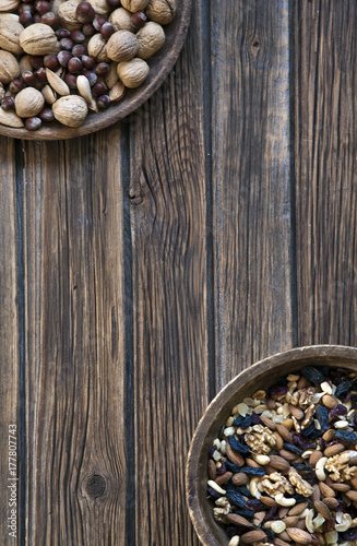 Nuts and dried fruits in wooden bowl on rustic wooden background. Top view, close up