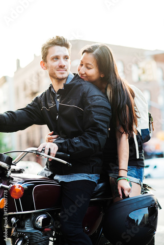 A man and woman sit on a motorcycle in the city. photo