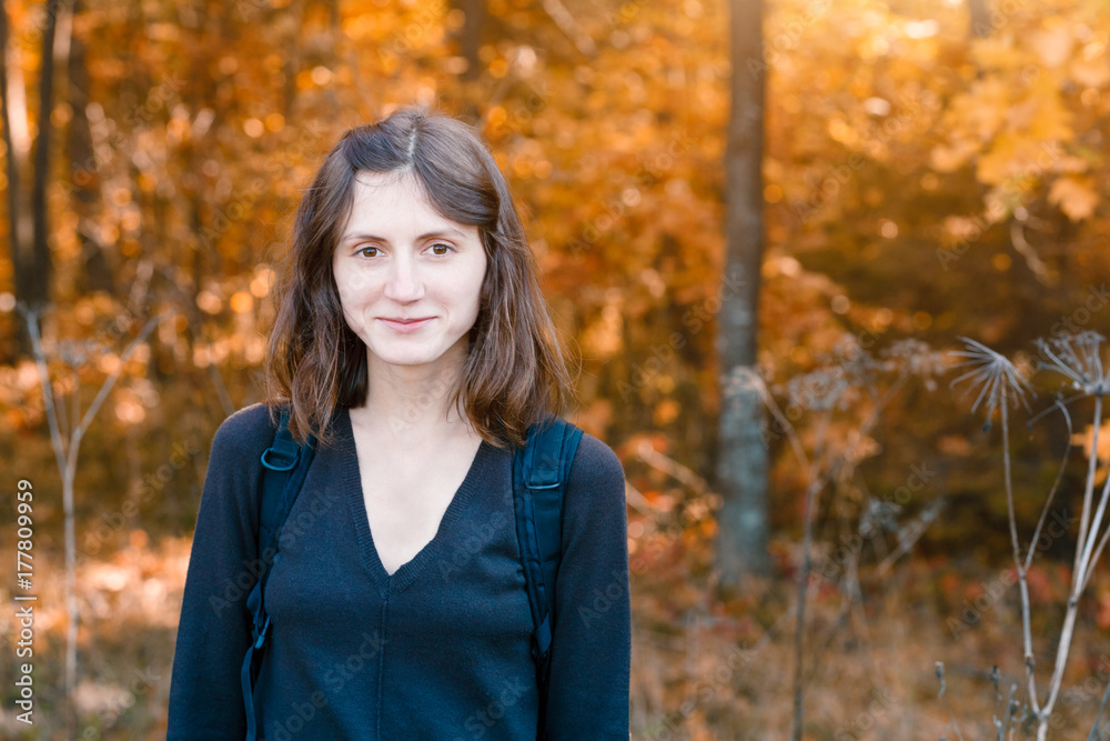 young woman with backpack smiling in autumn forest young woman with backpack smiling in autumn forest