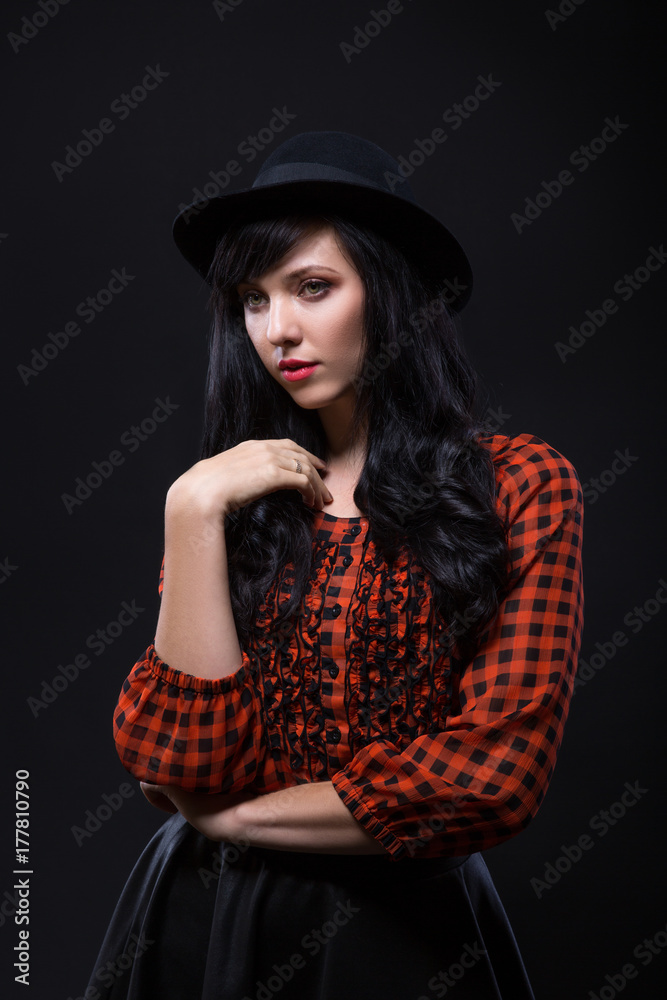 Emotion brunette female model posing in black hat with red bright lipstick on black background. Art fashion portrait. Emotion brunette female model posing in black hat with red bright lipstick on black background. Art fashion portrait.