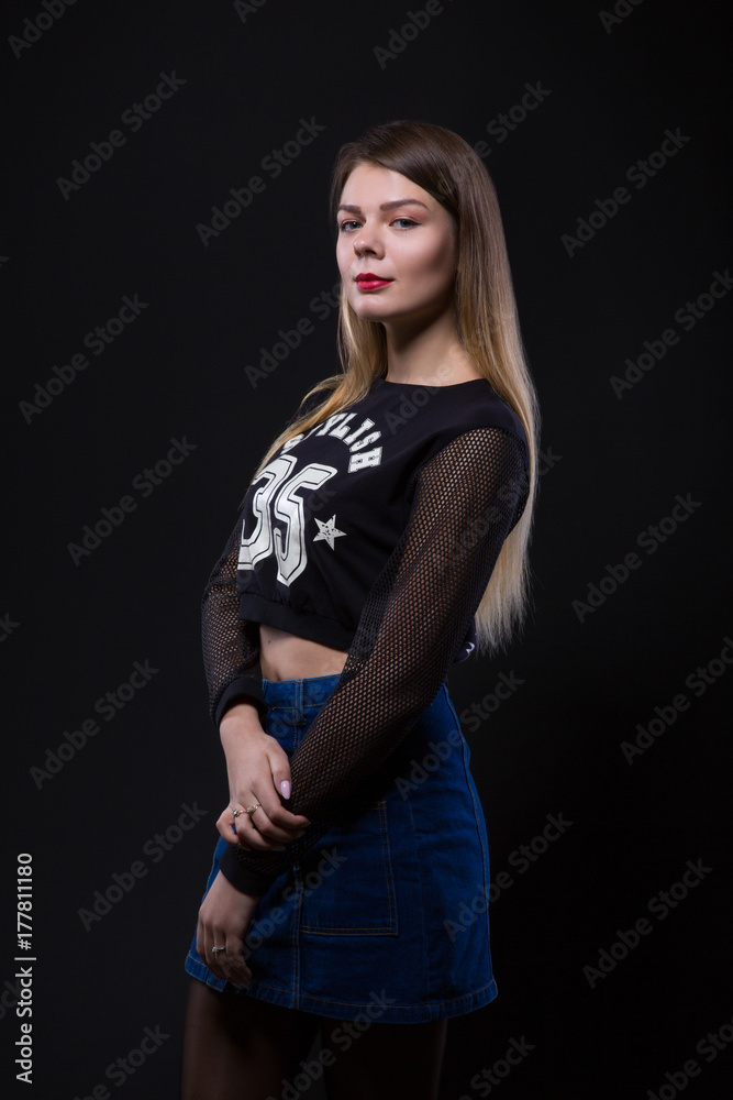 Pretty Femail model posing in denim skirt over black background Pretty Femail model posing in denim skirt over black background