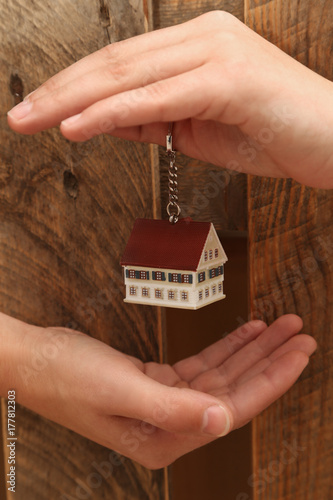 Eigenheim, Hausmodell in menschlichen Händen mit einem hölzernen Hintergrund © Alexander