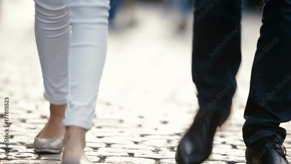 A young couple, a man and a woman, walk around the city, along the pavement. Legs close-up. A young couple, a man and a woman, walk around the city, along the pavement. Legs close-up.