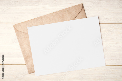 Blank white card and envelope on wooden table