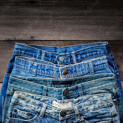 Blue jean and jean lack texture on the wooden floor, Pattern of blue jeans are overlapping on the table and free space.