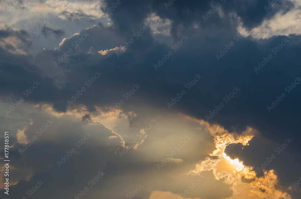 Golden sunlight beam through dark rainy cloud sky before sunset in rain season