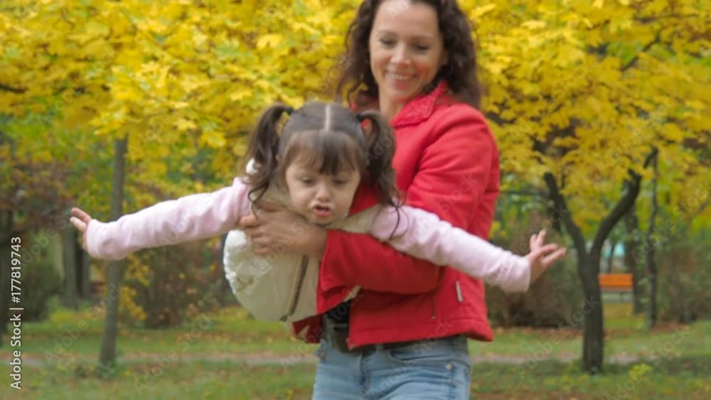 A woman with a child is playing in an autumn park. Mother and daughter are playing a plane. A woman with a child is playing in an autumn park. Mother and daughter are playing a plane.