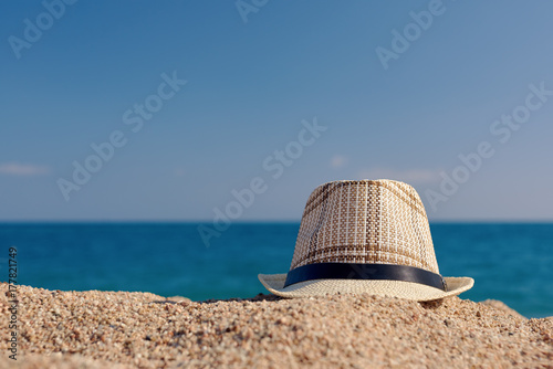 Men’s sunhat on the beach sand against sea.