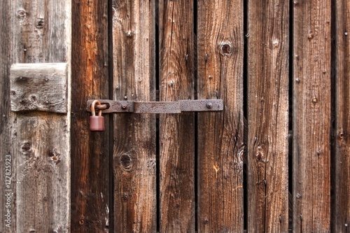 An old rusty lock on a wooden door. Protection against theft. A safe house.