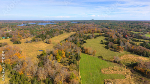 Aerial View of Farmlands and Patches of Trees in Fall with Lakes in the Distance