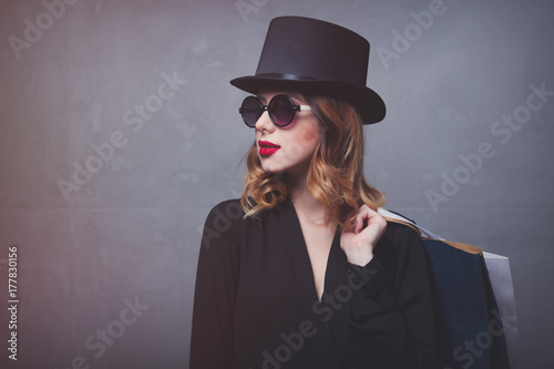 Style redhead girl in top hat with shopping bags