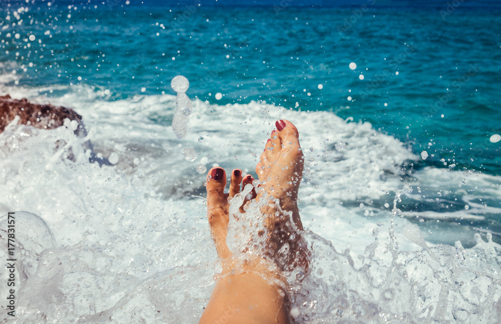 Female legs covered with a splash of a sea wave
