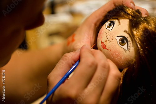 Painting face hand sewing home-made doll. photo