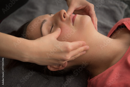 Girl has a Thai massage and face massage performed by young female masseur