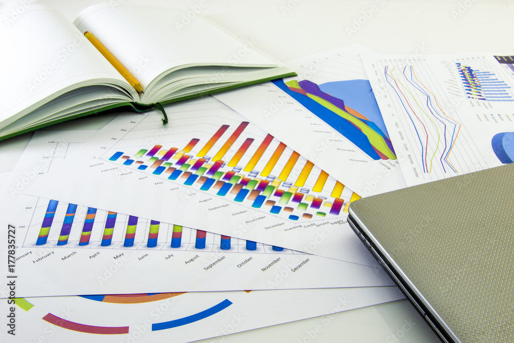 Preparing report. Blue graphs and charts. Business reports and pile of documents on gray reflection background. Preparing report. Blue graphs and charts. Business reports and pile of documents on gray reflection background.