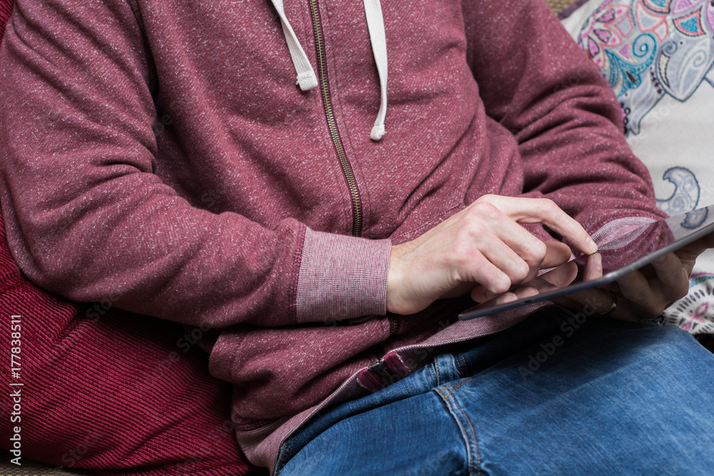A man relaxes at home using a tablet on the sofa A man relaxes at home using a tablet on the sofa