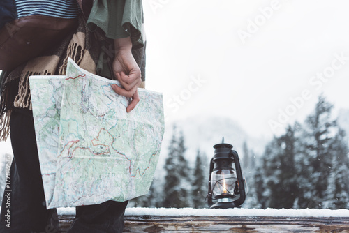 Canvas-taulu Woman standing in the wild with map and oil lamp