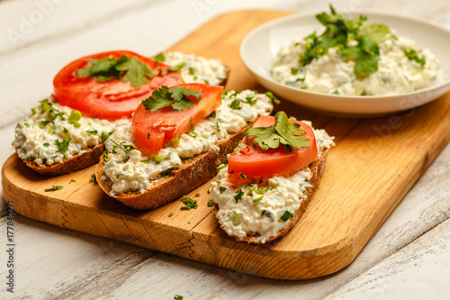 Sandwiches with healthy rye bread, cheese cream, tomatoes on white wooden table. Love for a healthy food