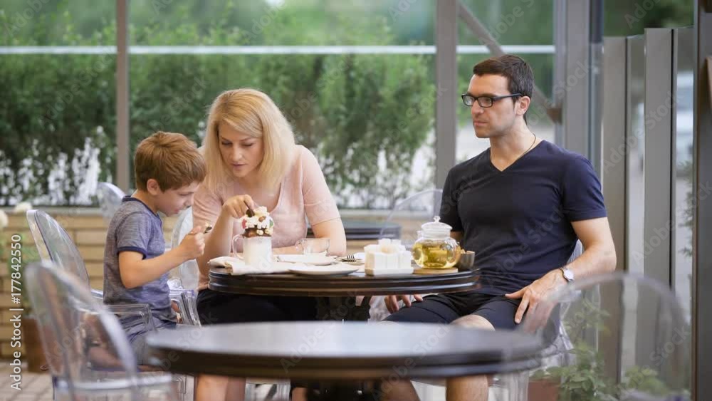 Mother watching boy eating while dining together on terrace of restaurant Mother watching boy eating while dining together on terrace of restaurant