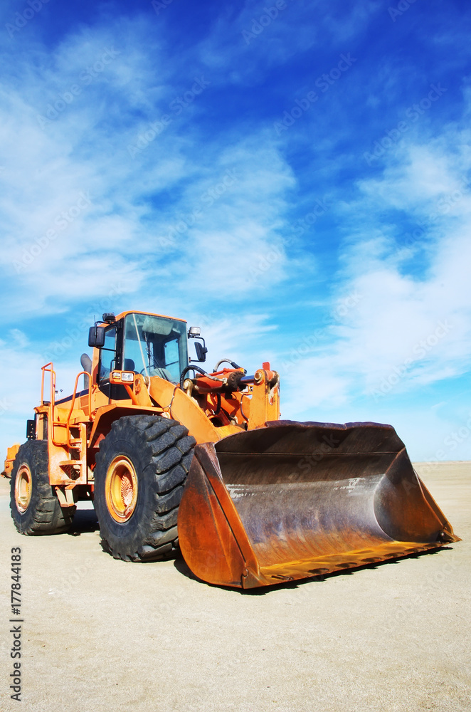 Fototapeta premium Orange loader bulldozer with cloud sky
