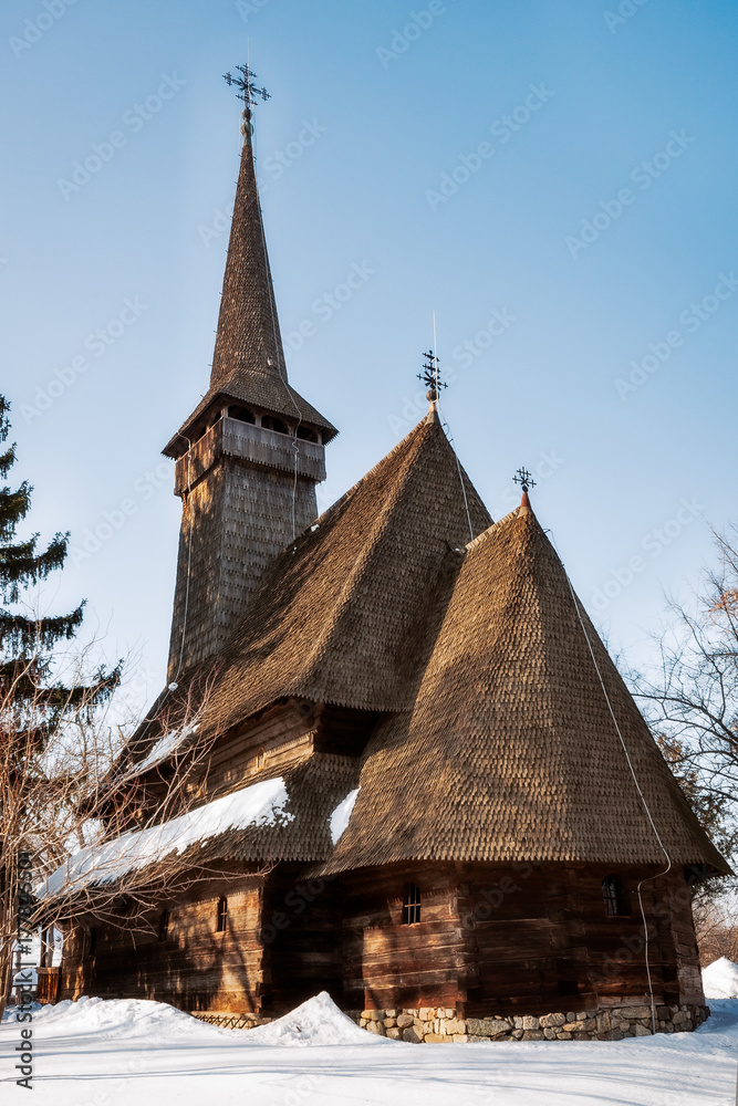 Traditional wooden Church with a bell tower surrounded by snow at the open-air ethnographic Village Museum in Bucharest, Romania Traditional wooden Church with a bell tower surrounded by snow at the open-air ethnographic Village Museum in Bucharest, Romania