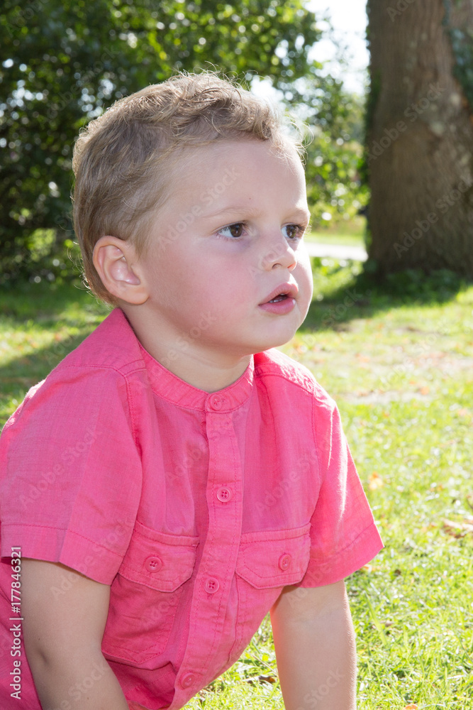 Spring or summer portrait of cute young boy playing with flower outdoors in clover field Spring or summer portrait of cute young boy playing with flower outdoors in clover field