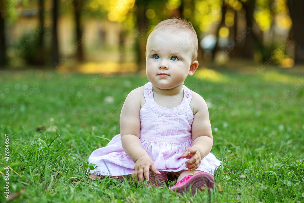 Little beautiful child sitting on the grass. The concept of children, childhood, lifestyle, family. Little beautiful child sitting on the grass. The concept of children, childhood, lifestyle, family.