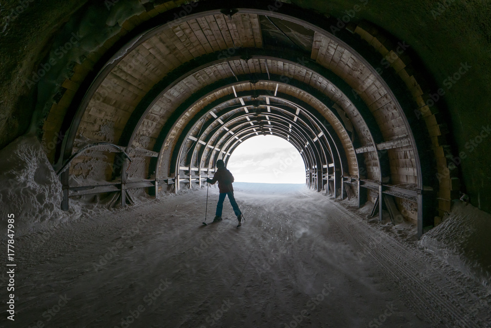 Tunnel for skiers, outdoor passage in ski resort, man skiing on snow