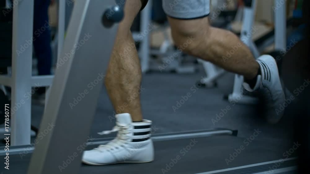 Strong man in the gym - bodybuilder running on the running track in the gym Strong man in the gym - bodybuilder running on the running track in the gym