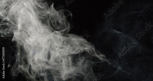 Wispy tower of smoke on left side of dark background