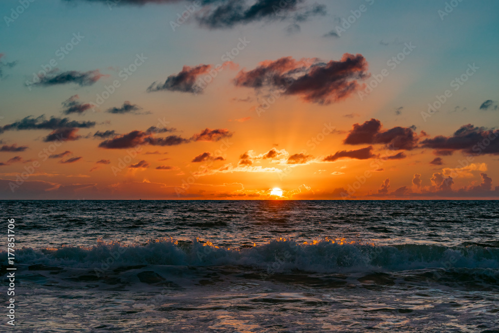 sun rising on the horizon over wavy ocean water