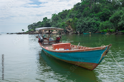 handmade, wooden fishing boat in the blue and green waters of Cambodia