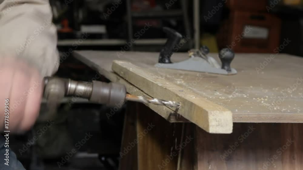 Man operating old hand drill, boring a piece of wood Man operating old hand drill, boring a piece of wood